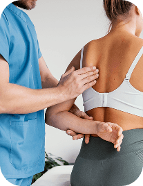 A physical therapist's hands guide and support a woman's lower back as she remains seated.